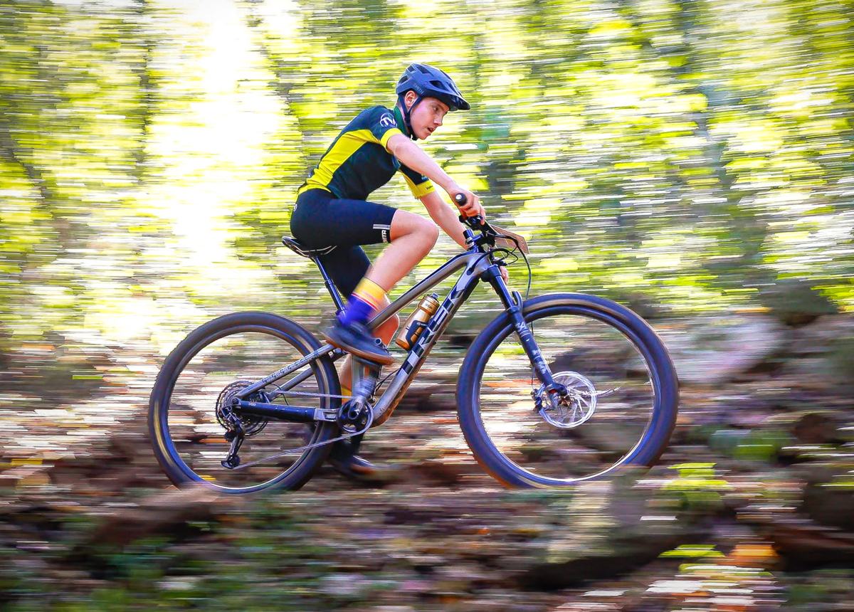A rider at speed through forest, the background blurred by motion
